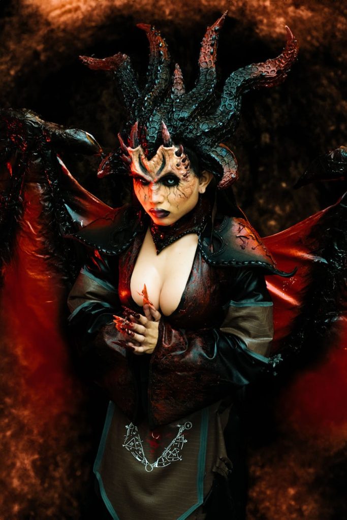 Woman in intricate devil cosplay with SFX makeup, horns, and eerie details.